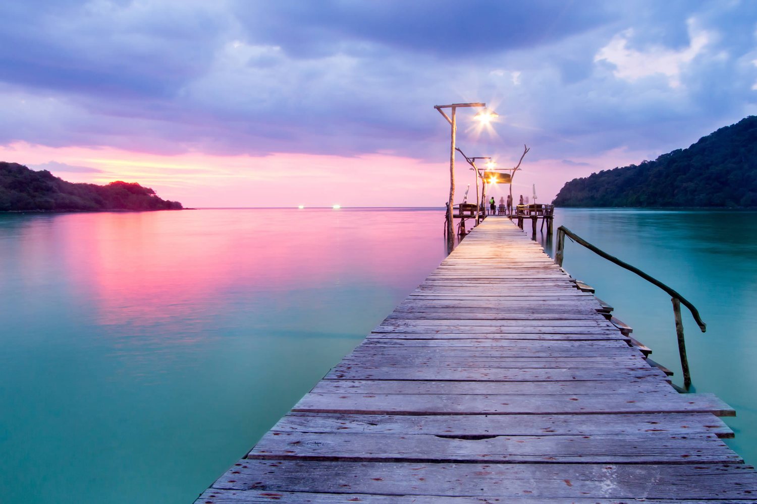 A calm wooden pier reaching out over still water at sunset